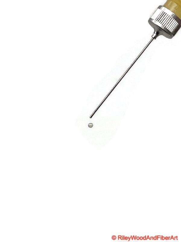 Oil Bottle with Precision Needle Tip showing one drop about one inch away from the tip falling as a round orb.