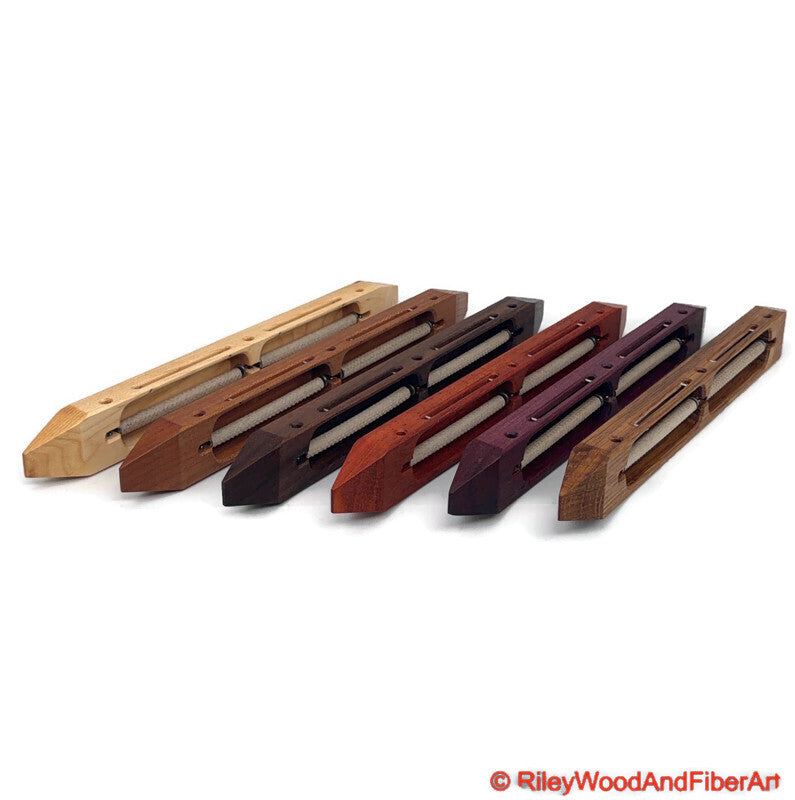 An array of closed bottom double bobbin boat shuttles standing on edge on a white background