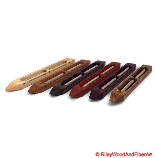 An array of closed bottom double bobbin boat shuttles side by side on a white background