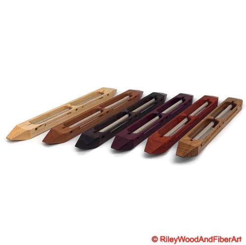 An array of open bottom double bobbin boat shuttles side by side on a white background